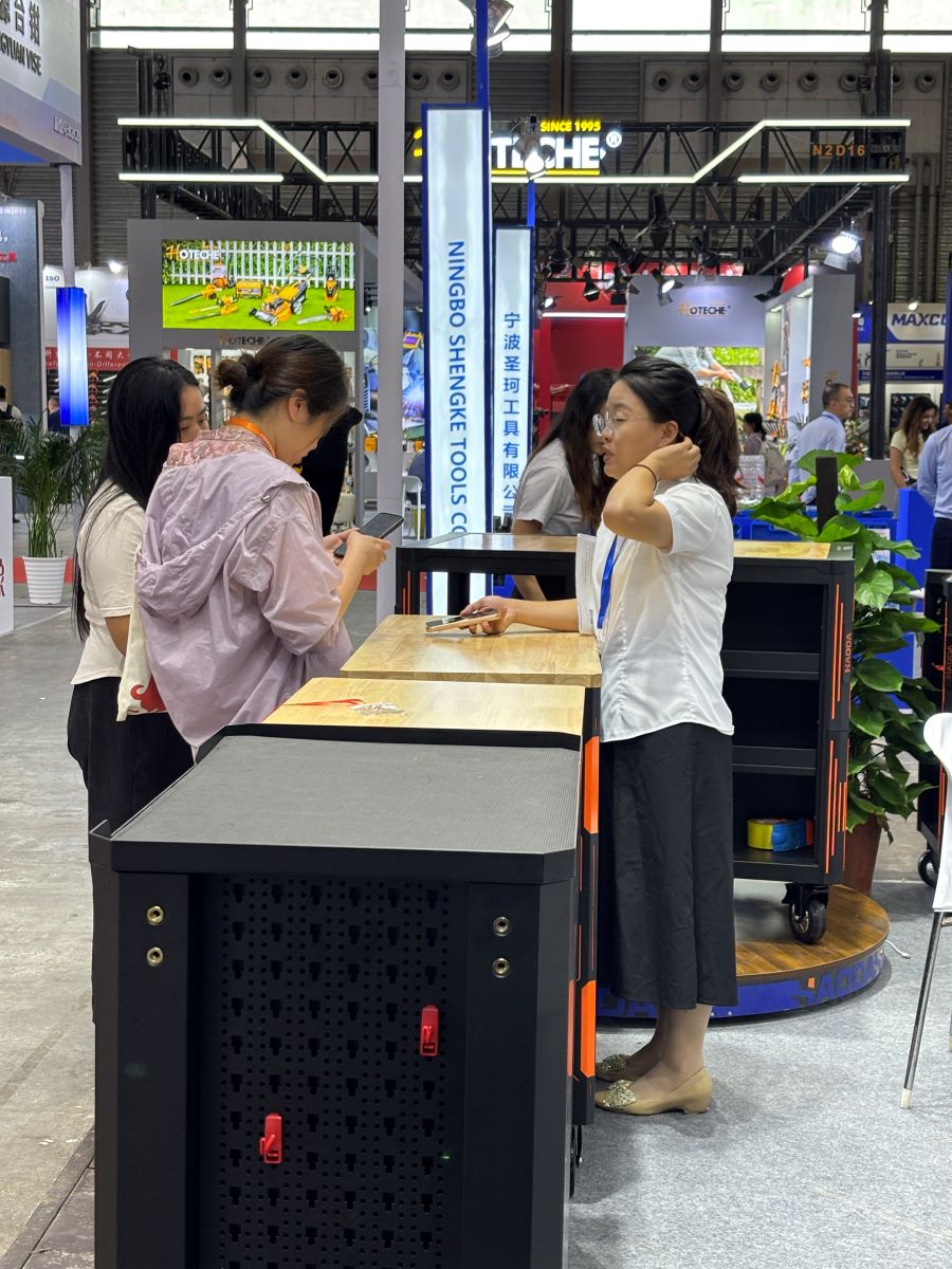 HAODA booth staff showing drawer interlock anti-tip system on a heavy-duty tool cart at CIHS 2026 HAODA booth staff showing drawer interlock anti-tip system on a heavy-duty tool cart at CIHS 2026